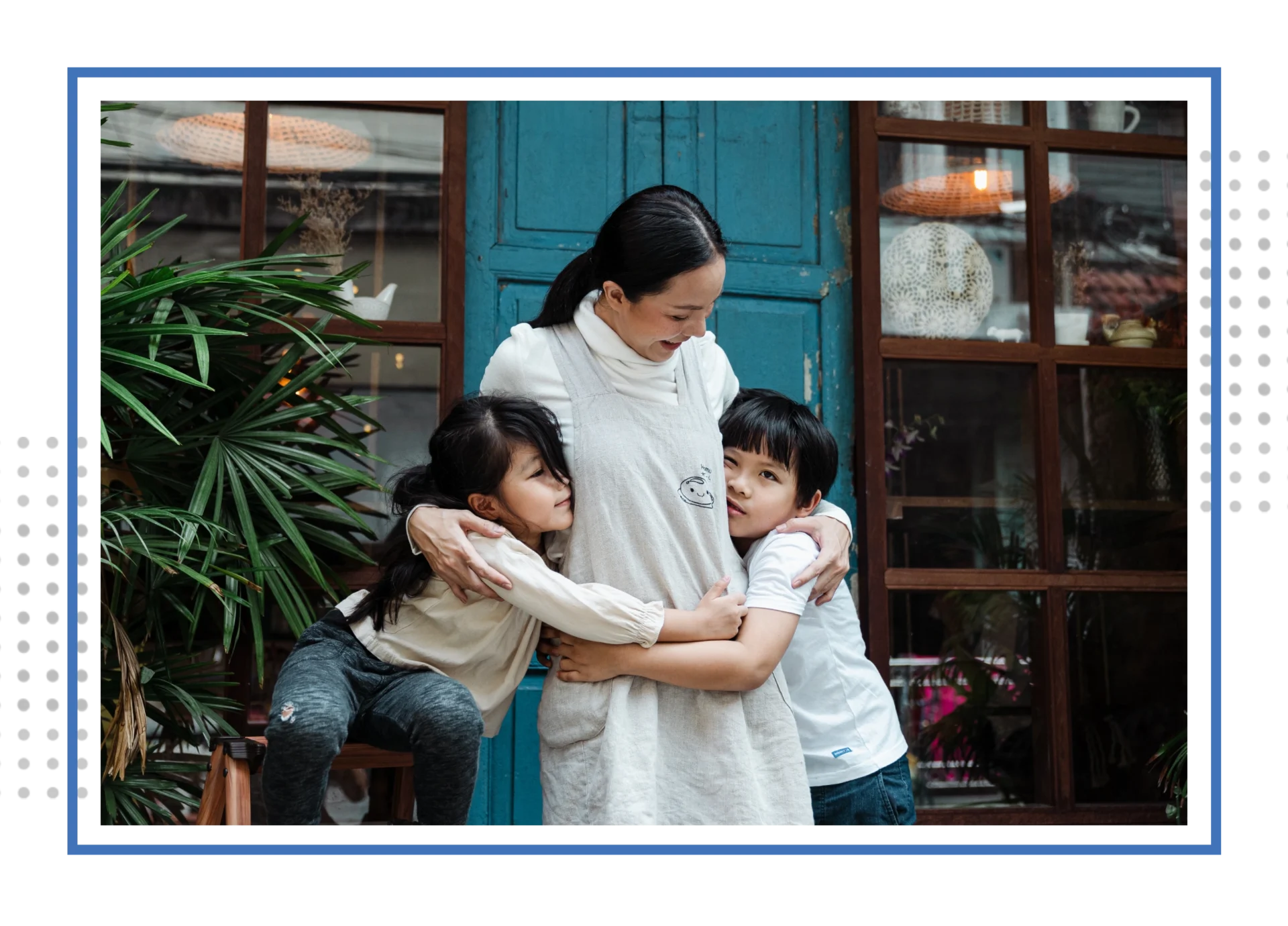 A woman and two children hug in front of a blue door.